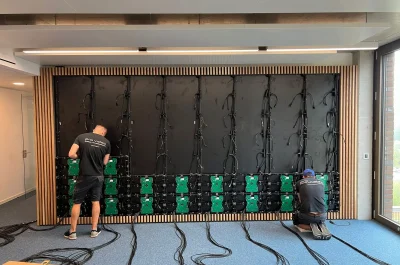 PRO VIDEO Techniker montieren mittlere LED-Modulreihen an vormontierter Rückwand im Seminarraum der Universität Bremen